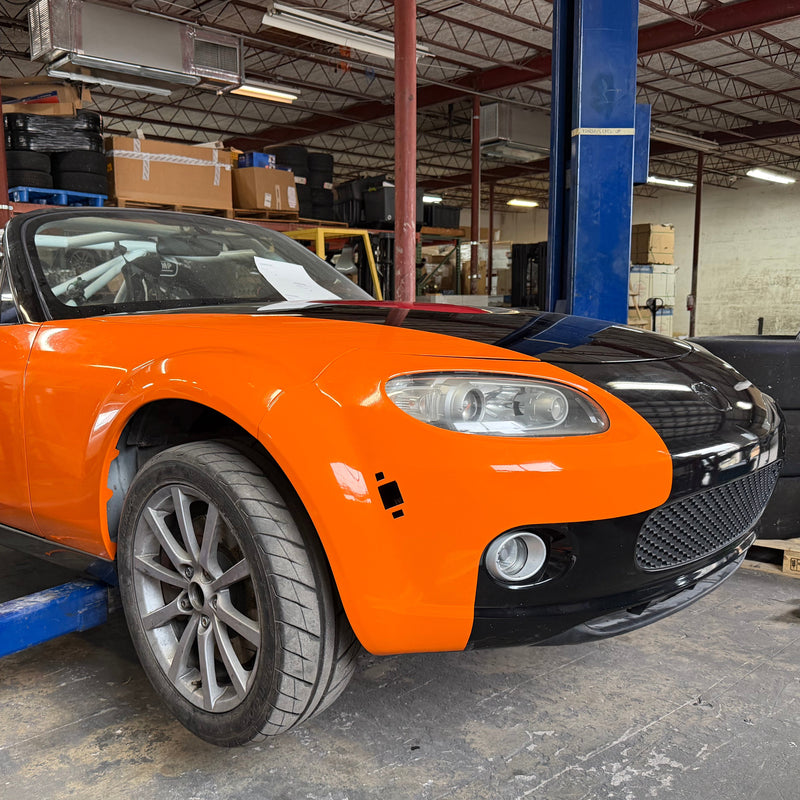 Orange and black car on a lift in a garage